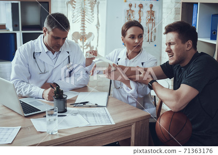 The doctor looks at the patient and bandages arm. The doctor looks at the patient and bandages arm. 71363176