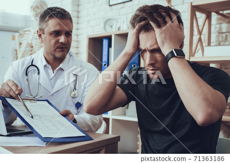 Male and female doctors with stethoscopes in office. Athlete is filling form on clipboard. Male and female doctors with stethoscopes in office. Athlete is filling form on clipboard. 71363186