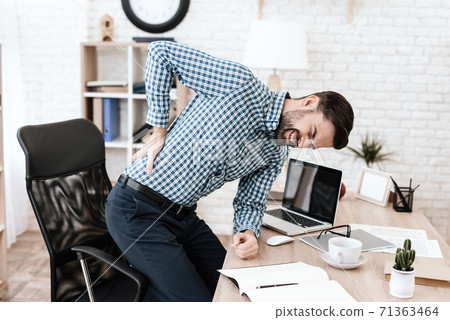 Man holding on to side while standing in an office Man holding on to side while standing in an office 71363464
