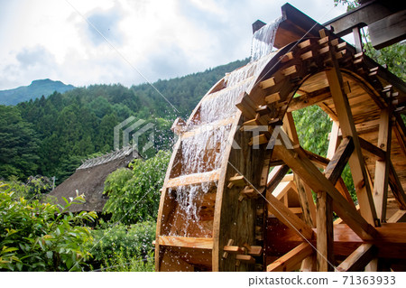 The mill wheel rotates under a stream of water. 71363933