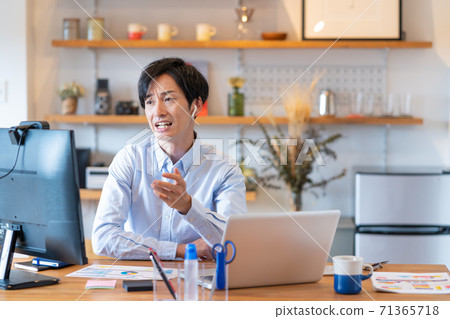 Telework: A young man with a troubled face having a web conference in his living room Telework: A young man with a troubled face having a web conference in his living room 71365718