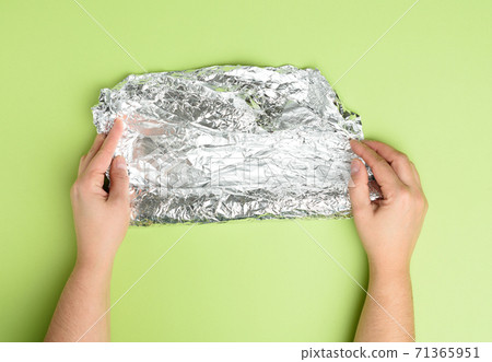 two female hands holds crumpled silver foil on a green background two female hands holds crumpled silver foil on a green background 71365951