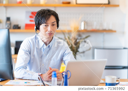 Telework A young man wearing a headset and having a web conference in his living room 71365992