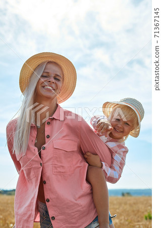 happy mother holding baby smiling on a wheat field in sunlight 71367145