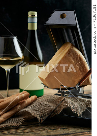 cheese as a perfect gourmet appetizer to a glass of white wine: bread sticks, parmesan served on a wooden board, on a black background cheese as a perfect gourmet appetizer to a glass of white wine: bread sticks, parmesan served on a wooden board, on a black background 71367181