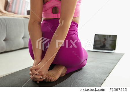 Close up of beautiful young woman working out indoors, doing yoga exercise on gray mat, details 71367235