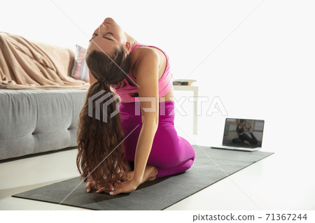 Beautiful young woman working out indoors, doing yoga exercise on gray mat at home Beautiful young woman working out indoors, doing yoga exercise on gray mat at home 71367244