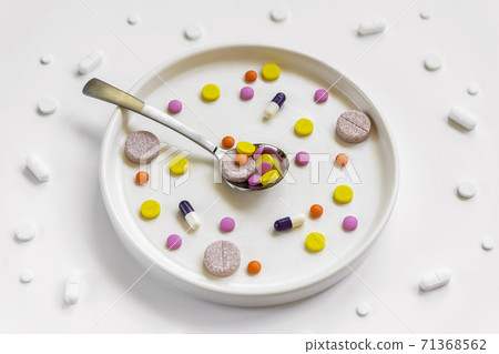 Plate and spoon with set of pills, tablets, vitamins, drugs, capsules, medicament and food supplement for health care. Pharmacy theme, medical background 71368562
