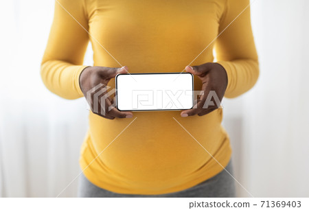 Unrecognizable pregnant black woman showing mobile phone with empty display 71369403