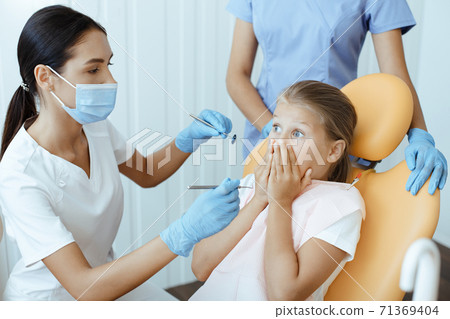 Child, in horror, close with hands and looks at millennial woman doctor in white uniform 71369404