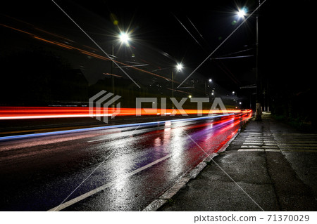 Lights of cars at night. Street lights. Night city. Long-exposure photograph night road. Wet road after rain. Lights of cars at night. Street lights. Night city. Long-exposure photograph night road. Wet road after rain. 71370029