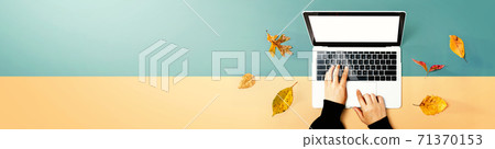 Autumn leaves with person using a laptop computer Autumn leaves with person using a laptop computer 71370153