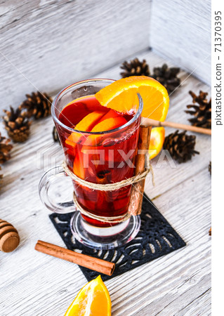 Christmas mulled wine with spices and orange on wooden rustic background. Selective focus. Anise stars and cinnamon sticks. Christmas cones. 71370395