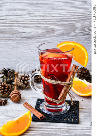 Christmas mulled wine with spices and orange on wooden rustic background. Selective focus. Anise stars and cinnamon sticks. Christmas cones. Christmas mulled wine with spices and orange on wooden rustic background. Selective focus. Anise stars and cinnamon sticks. Christmas cones. 71370396