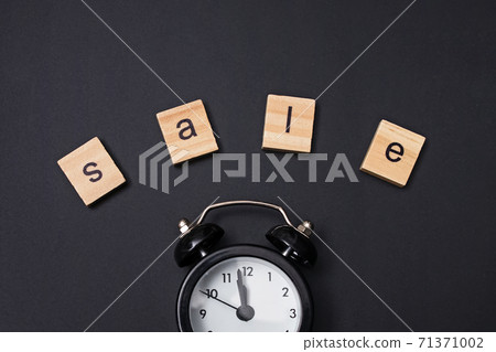 Small alarm clock and word Sale on black background 71371002