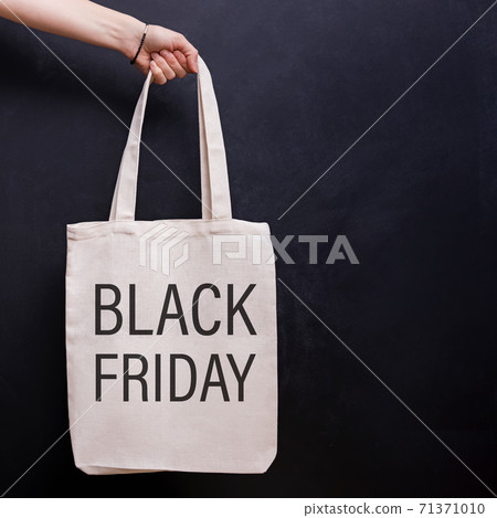 Crop view of woman hand holding paper shopping bag by handles on red background Crop view of woman hand holding paper shopping bag by handles on red background 71371010