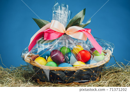 Easter gift basket with multicolor eggs, blue background Easter gift basket with multicolor eggs, blue background 71371202