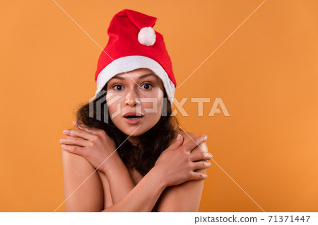 A young woman in a Santa Claus hat. Portrait on a yellow background. Christmas concept. A young woman in a Santa Claus hat. Portrait on a yellow background. Christmas concept. 71371447