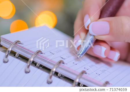Woman putting mark on check boxes of to do list in notebook - close up 71374039