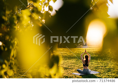 Back view of flexible woman raising arms up and folding them together above head in Namaste position Back view of flexible woman raising arms up and folding them together above head in Namaste position 71374486