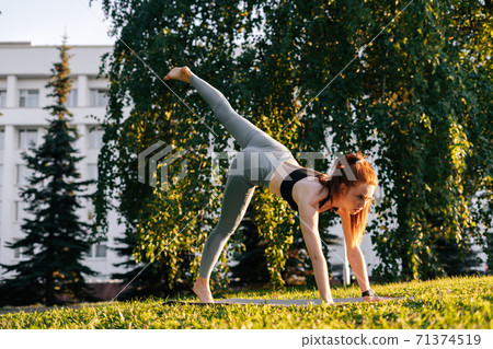 Low-angle shot of young woman practicing yoga in down facing dog pose on one leg 71374519