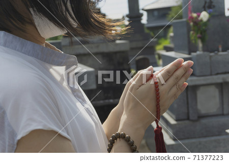 一名戴著口罩防止感染的婦女祈禱並參觀墳墓 71377223
