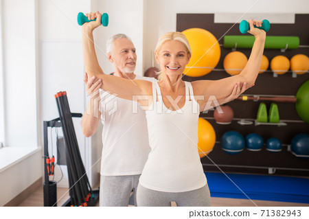 Mature man instructing blonde woman in gym Mature man instructing blonde woman in gym 71382943
