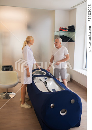 Grey-haired male patient talking to the doctor near apparatus 71383098