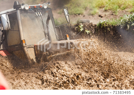 Off-road racing car driving at high speed on a dirt road with a smeared background. The concept of extrieme offroad Off-road racing car driving at high speed on a dirt road with a smeared background. The concept of extrieme offroad 71383495