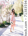 Cheerful woman on alley with magnolia trees. Soft focus. 71383594
