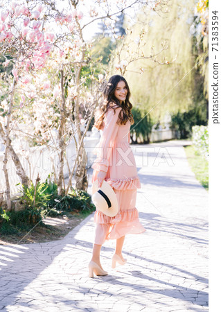 Cheerful woman on alley with magnolia trees. Soft focus. 71383594