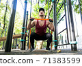 Athlete doing exercise with elastic band on sports ground 71383599
