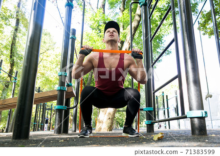 Athlete doing exercise with elastic band on sports ground 71383599