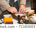 Men's hands roll up a cigar of high quality raw materials using vintage wooden cigar making tools 71383603