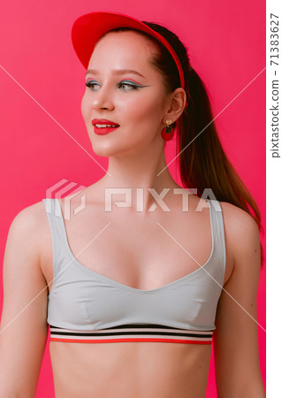 Portrain slim fit sport body young sexy woman in retro swim suit bra and red cap with clean skin beautiful creative pin-up make-up smiling looking aside isolated over pink background 71383627
