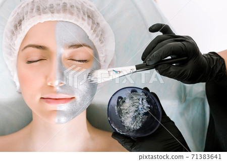 medical procedure. The process of applying a beauty mask to the skin of a patient with her eyes closed lying on a pillow. the concept protection and retardation against ageing and skin care 71383641