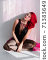 Verticled portrait of a red hair woman sitting on the floor by the wall with her eyes closed in a black body suit in rays of light falling from the window. Relaxation stimulate mental health 71383649
