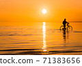 A rider rides his bike along the surf line at sunset. Silhouette of a man engaged in pleasant sports activities, rest and mental recuperation , away from other people 71383656