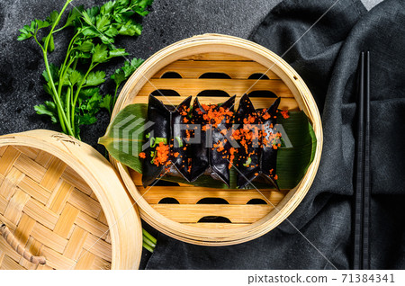 Black Dim sum dumplings in bamboo steamer. Asian cuisine. Black background. Top view Black Dim sum dumplings in bamboo steamer. Asian cuisine. Black background. Top view 71384341