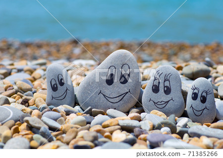 Pebbles with drawn faces in the sand. Father, mother, daughter and son. Family vocation concept. Pebbles with drawn faces in the sand. Father, mother, daughter and son. Family vocation concept. 71385266