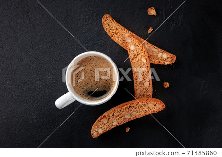 Biscotti. Italian almond cookies with a cup of coffee, shot from the top on a black background Biscotti. Italian almond cookies with a cup of coffee, shot from the top on a black background 71385860