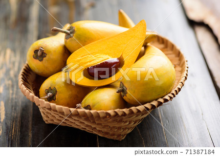 Eggfruit or canistel in a basket on wooden table, Thai fruit 71387184