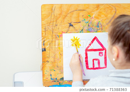 Child is drawing yellow sun with red house. Child is drawing yellow sun with red house. 71388363