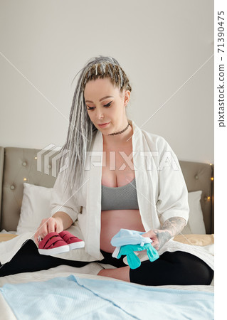 Pregnant woman preparing baby clothes 71390475