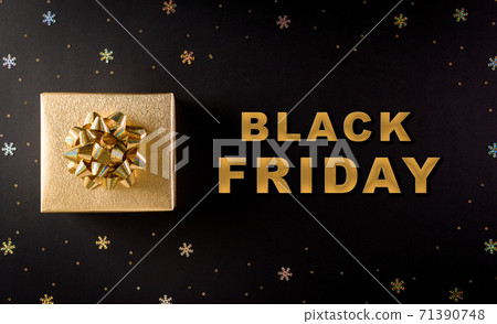 Top view of golden christmas gift boxes on black background with Black Friday text. Black Friday Sale, Banner, poster composition. 71390748