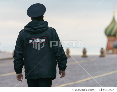 The celebration of Victory Day during coronavirus pandemic. Holidays without people. Police officer crossing Red Square. Rear view. Saint Basil's Cathedral as background 71390802