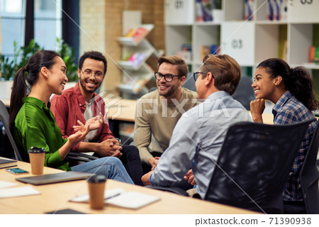 Creating success. Group of young happy multi racial business people communicating and sharing ideas while working together in the modern office Creating success. Group of young happy multi racial business people communicating and sharing ideas while working together in the modern office 71390938