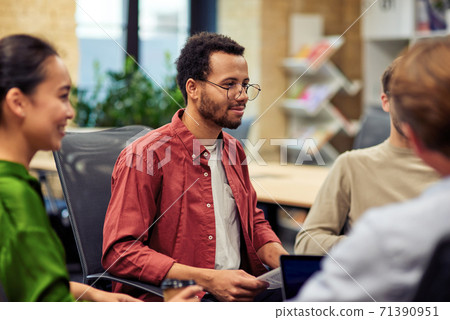 Young mixed race man looking attentively at colleague while having brainstorming meeting in the modern office Young mixed race man looking attentively at colleague while having brainstorming meeting in the modern office 71390951