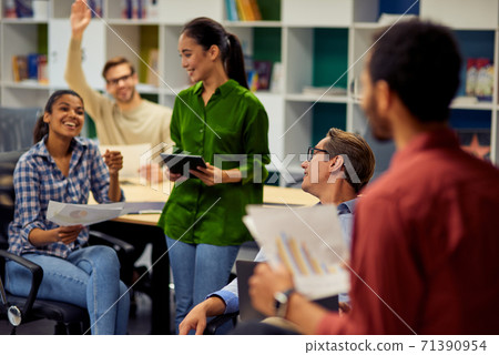 Group of young and happy diverse multi ethnic business people standing together in modern office and discussing project or sharing ideas Group of young and happy diverse multi ethnic business people standing together in modern office and discussing project or sharing ideas 71390954