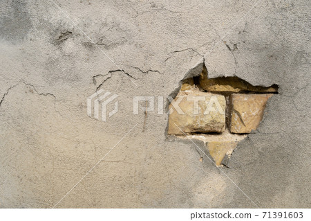 Brickwork is visible through hole in plaster on gray wall. Abstract background with space for text 71391603